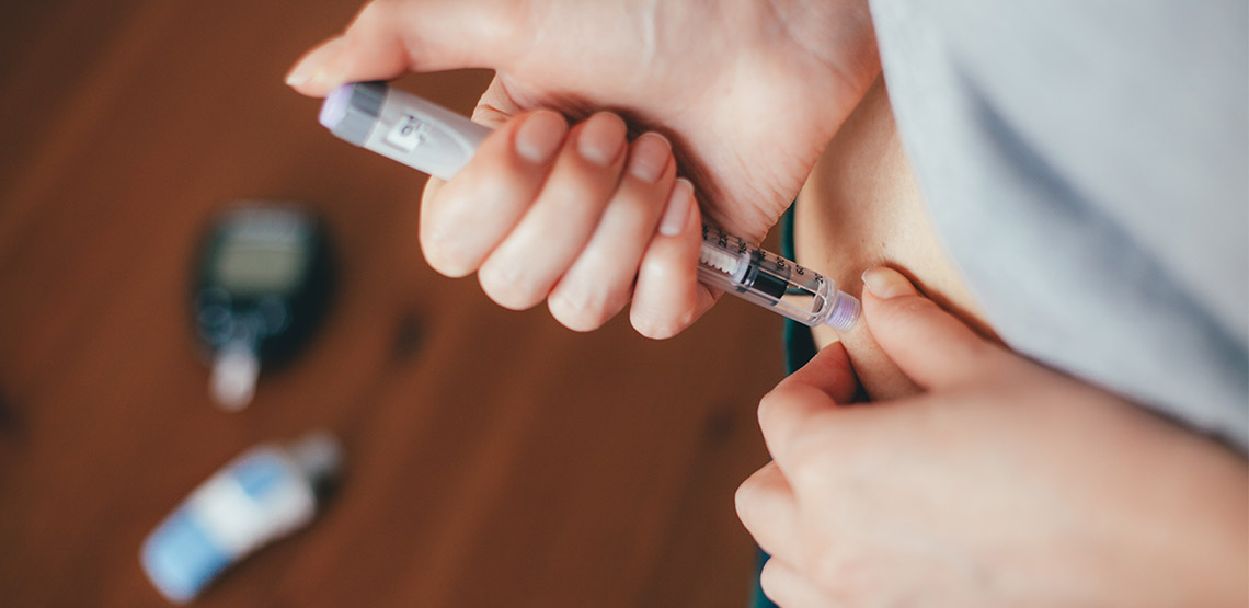 Woman injecting herself with an insulin pen in her stomach
