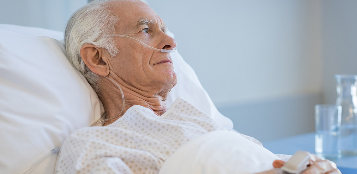 Older man in hospital bed wearing oxygen tubes in nose