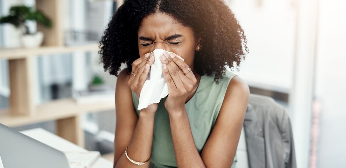 A woman blowing her nose due to allergies.