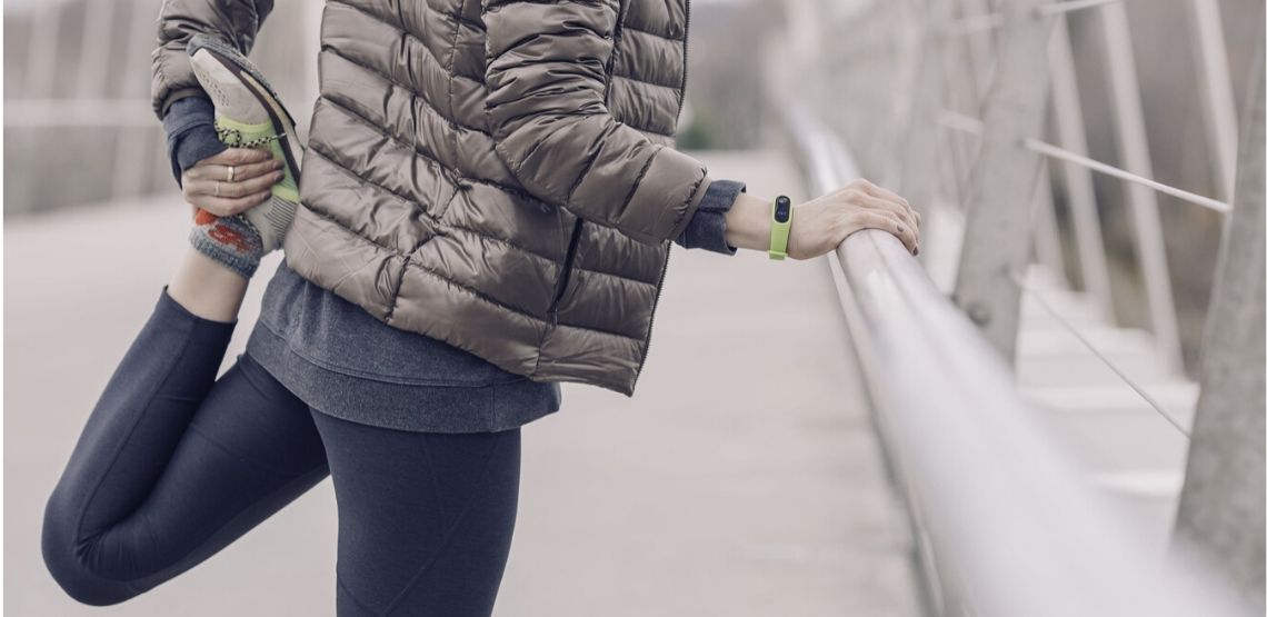 a woman stretching after exercising in cold weather (running)