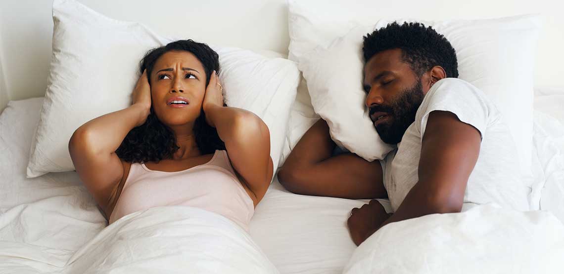 a frustrated woman being kept up by her partner's snoring