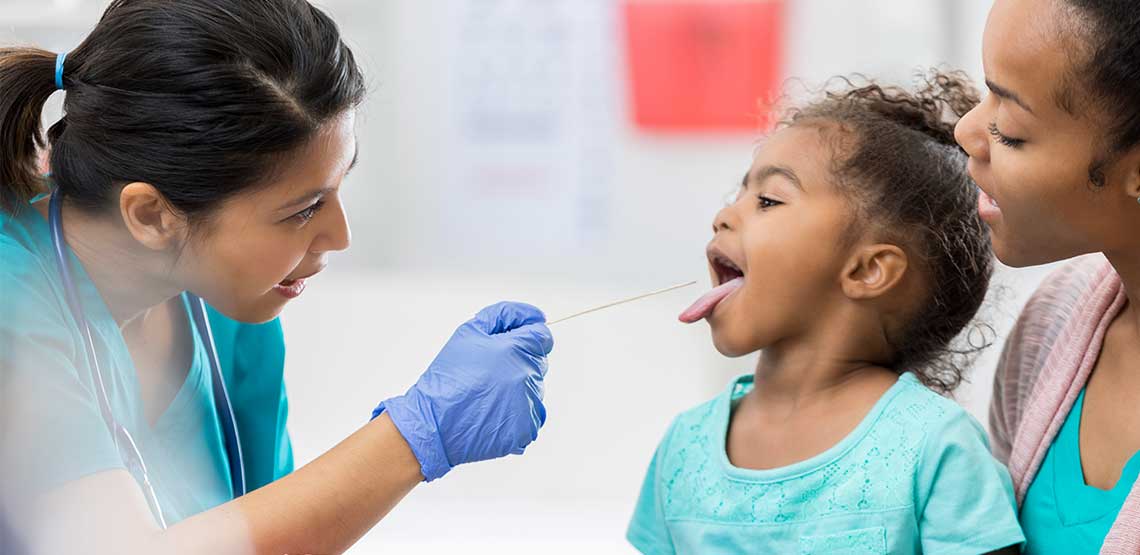a female doctor examining a young child's throat to check for symptoms of strep throat