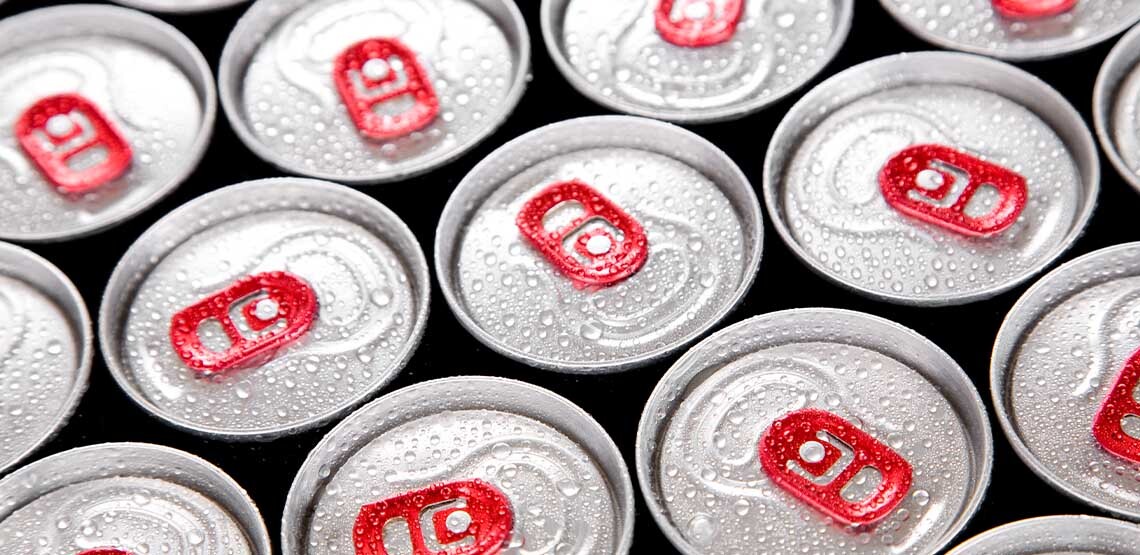 Several drink cans aligned together covered in water droplets