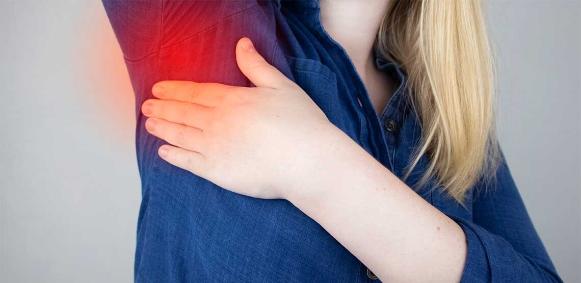 A person lifting up her right arm while holding her left hand against the armpit. The armpit has a red glow around it to represent inflammation and pain.