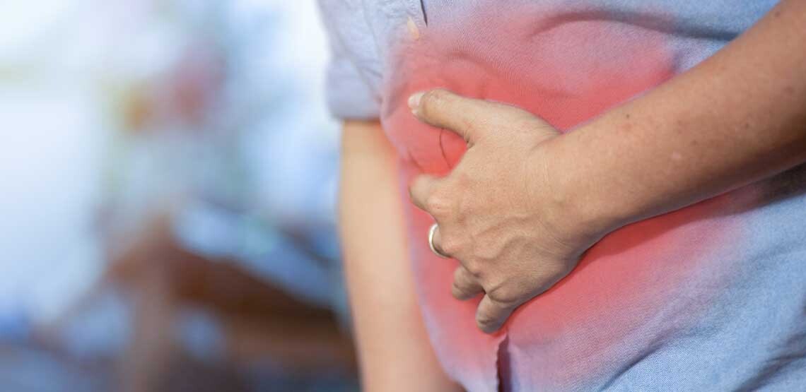 A man experiencing pain and holding stomach