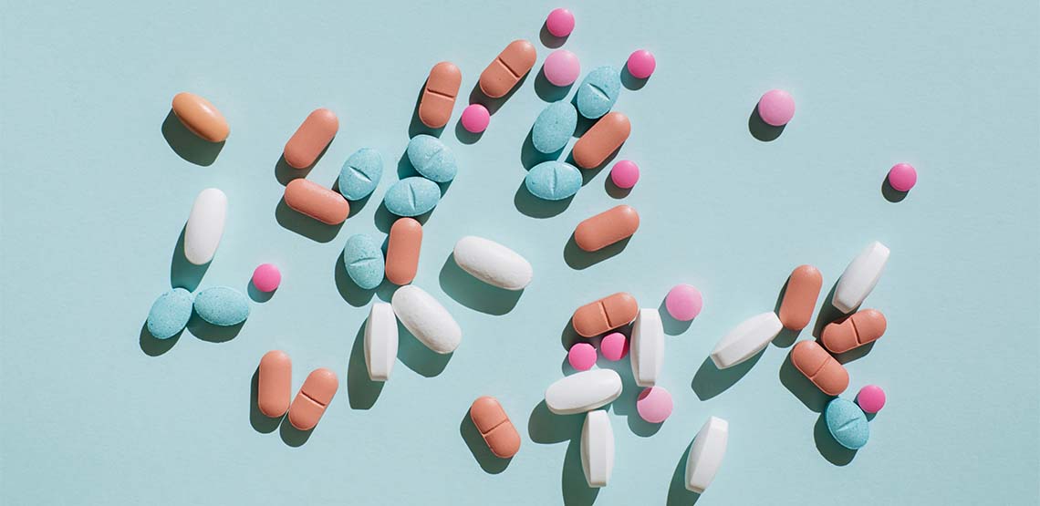 Blue, pink and white pills against a light blue background.